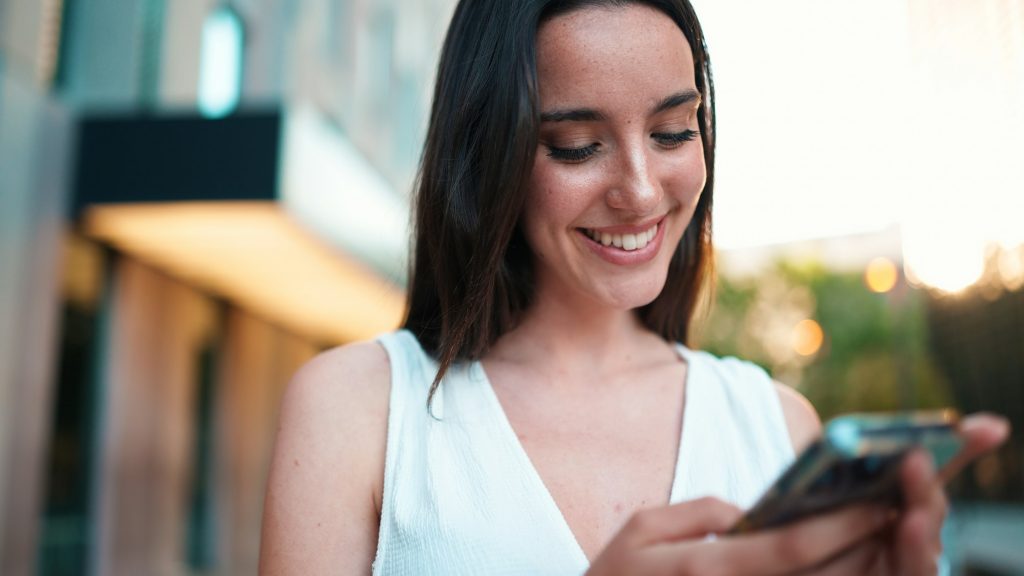 Beautiful woman with freckles and dark loose hair with smartphone