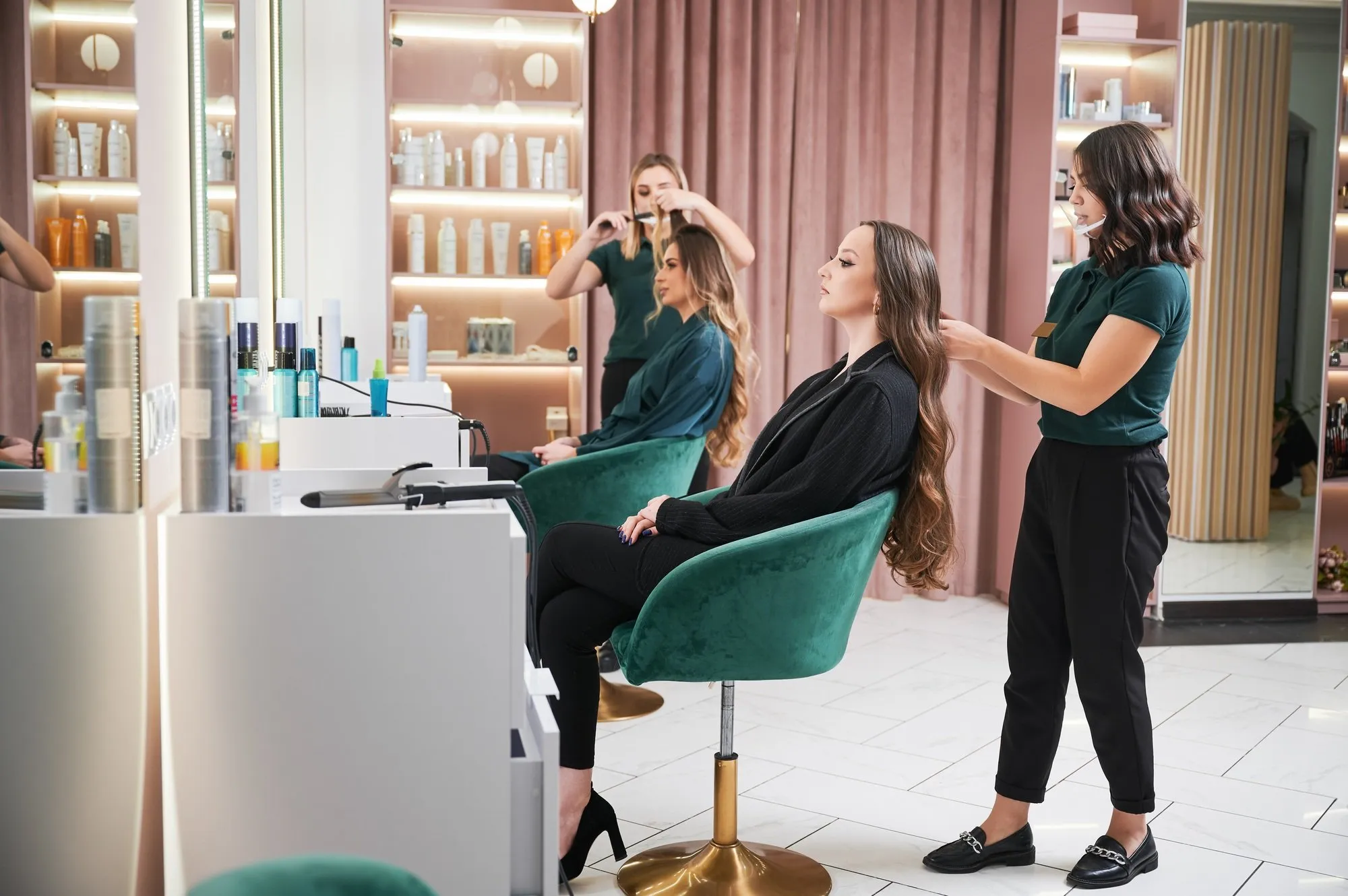 Hairdresser curling woman hair in beauty salon.